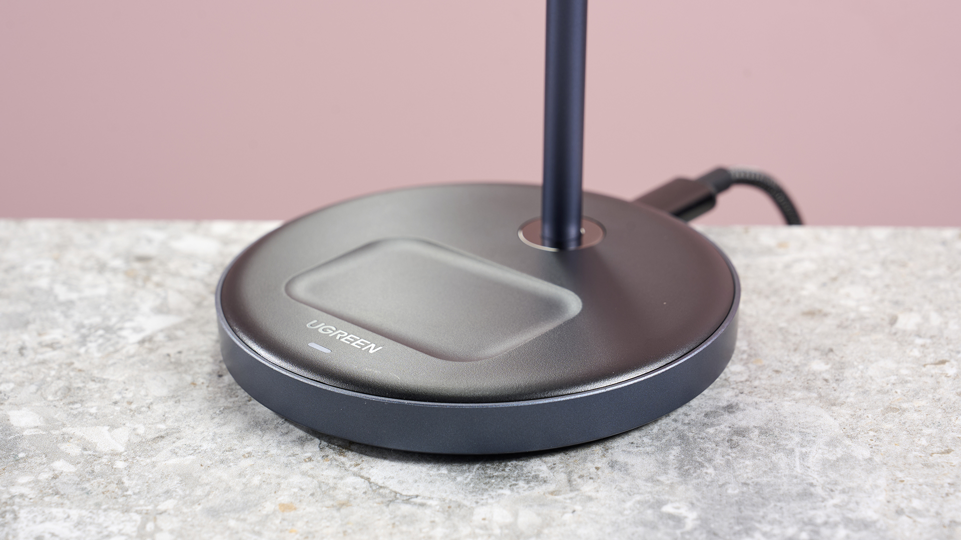 A close-up of the base of the Ugreen 2-in-1 charger, showing the AirPods charging pad and the charging indicator light.