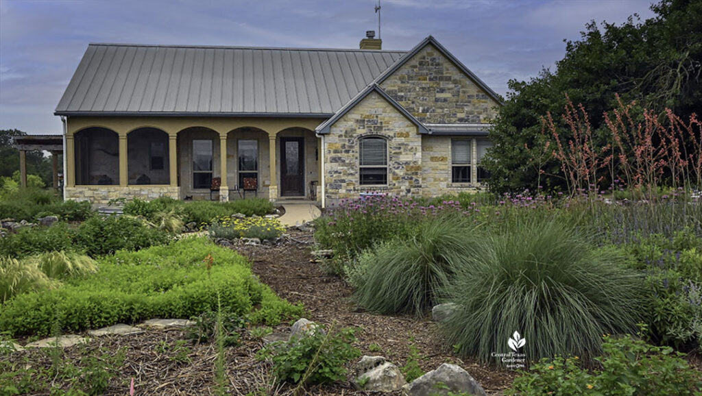 colorful perennials and clump grasses in front yard of stone house